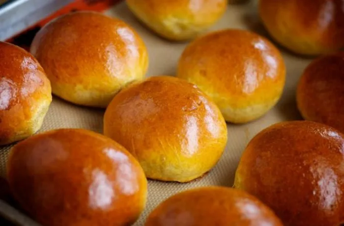 Bollos de leche o suizos Bollos de leche recién horneados y brillantes, pan dulce español (bollo suizo), receta tradicional de Madrid.